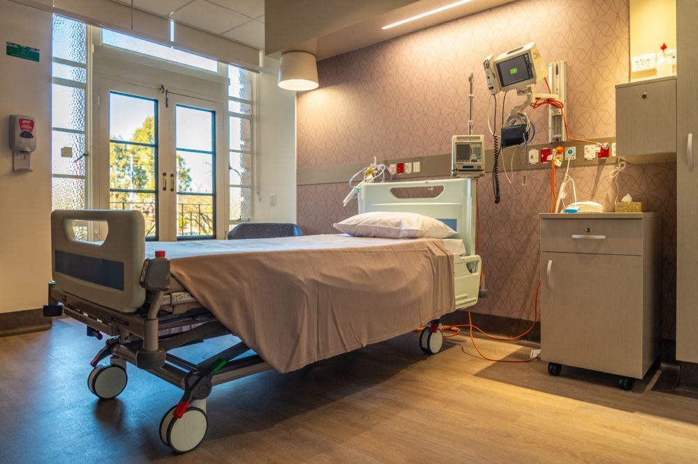 An empty hospital room with a bed and a window.