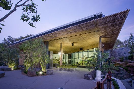 A large building with a roof made of bamboo and trees in front of it.