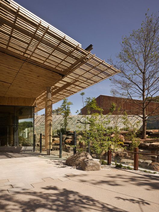 A building with a wooden roof is surrounded by trees and rocks