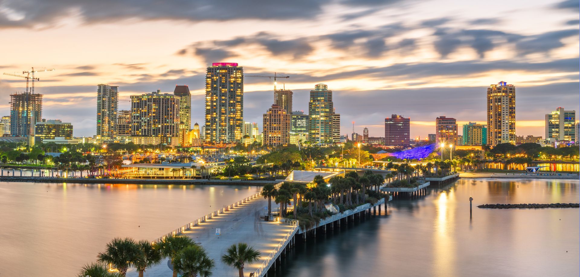 Three office workers smiling at a laptop screen in a bright office.
