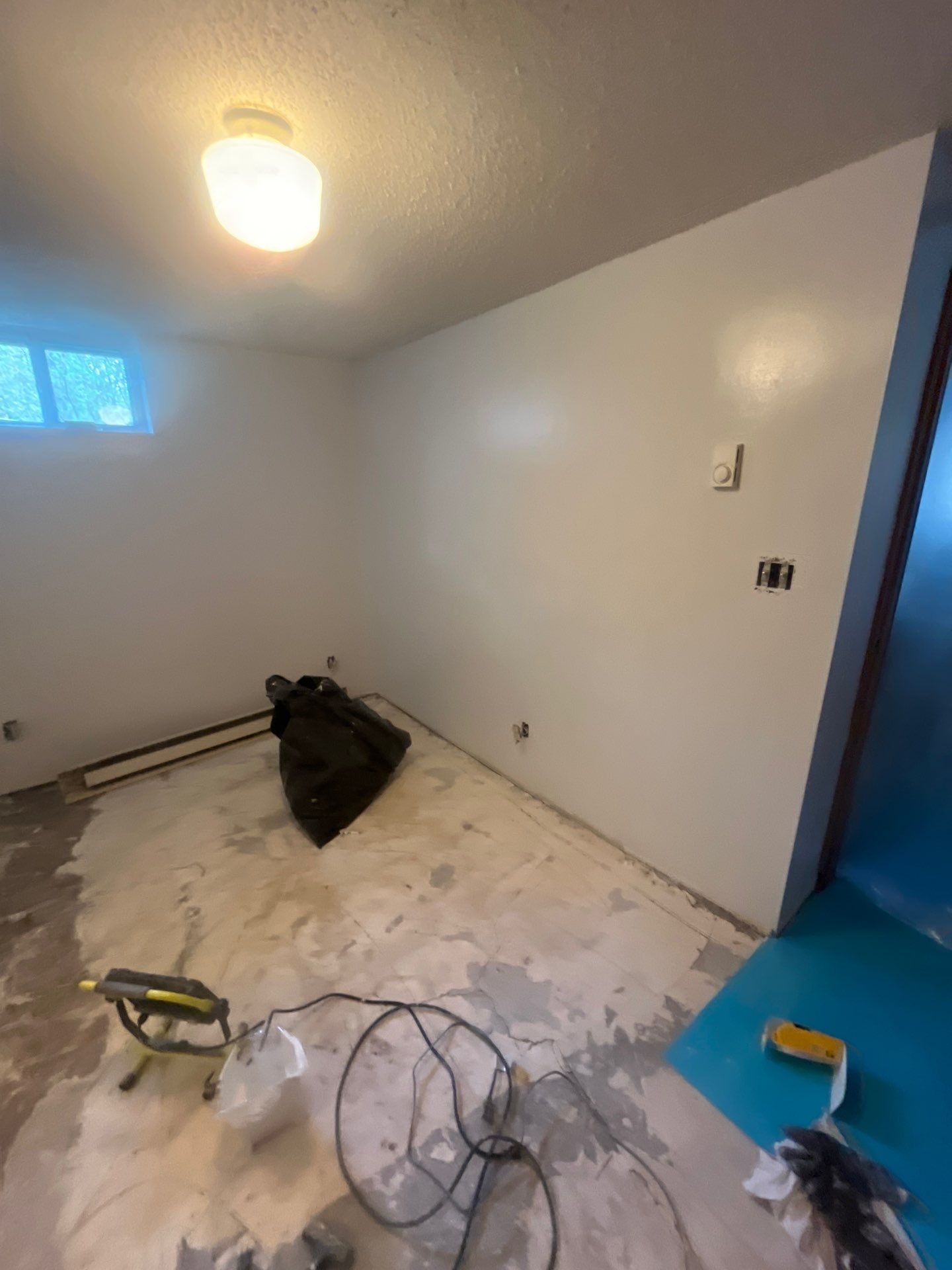 A room with white walls and a blue door is being remodeled.