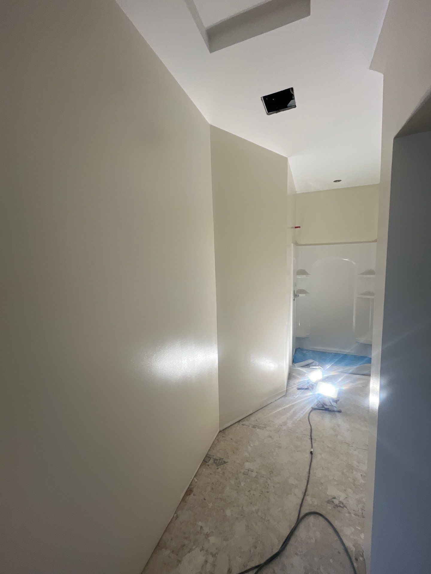 A room with white walls and a black cord hanging from the ceiling.