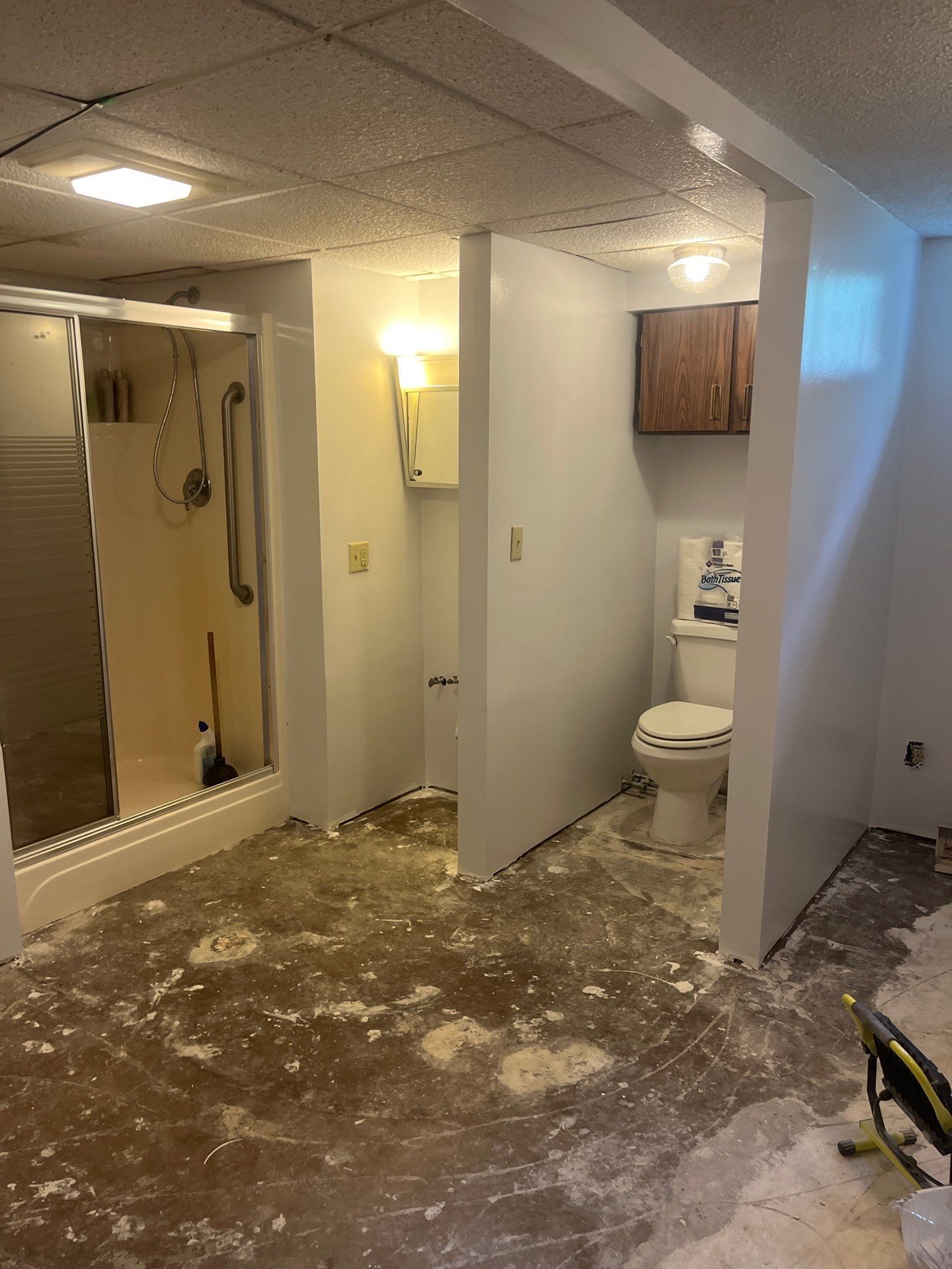A bathroom with a toilet , shower , and cabinets.