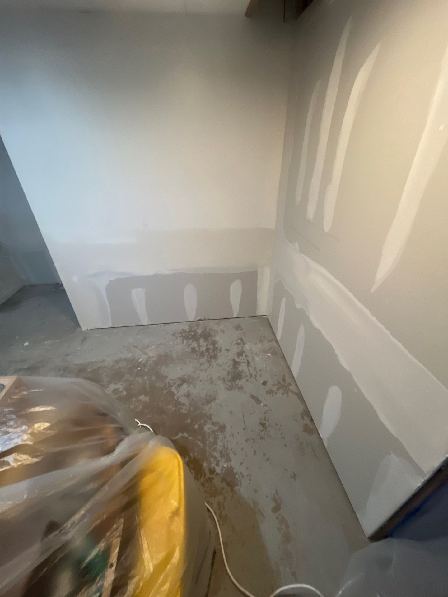A room with white walls and a yellow bag on the floor.