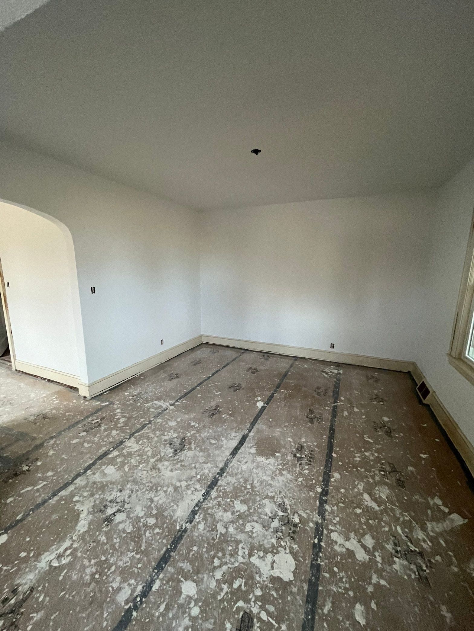 A large empty room with a wooden floor and white walls.