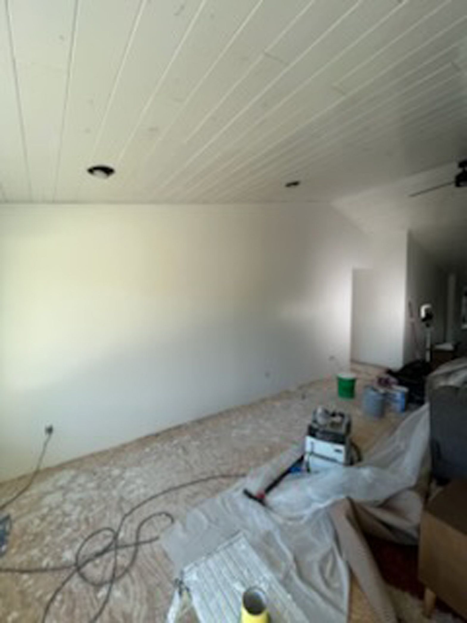 An empty room with white walls and a ceiling fan.