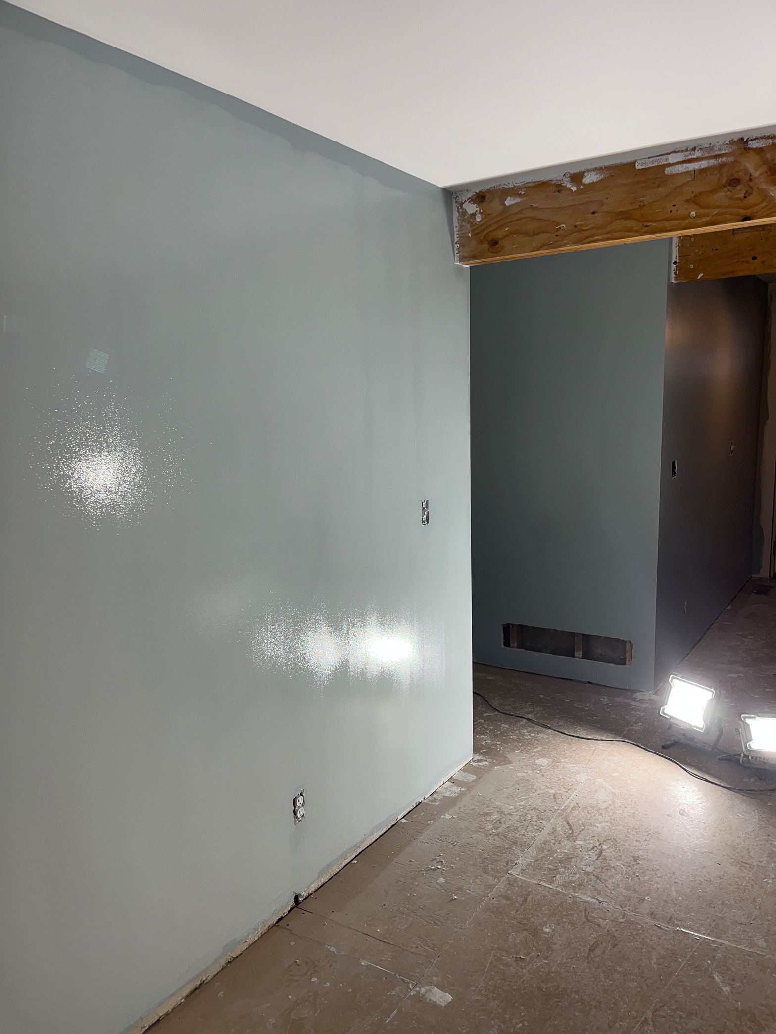 An empty room with a gray wall and a wooden beam in the ceiling.