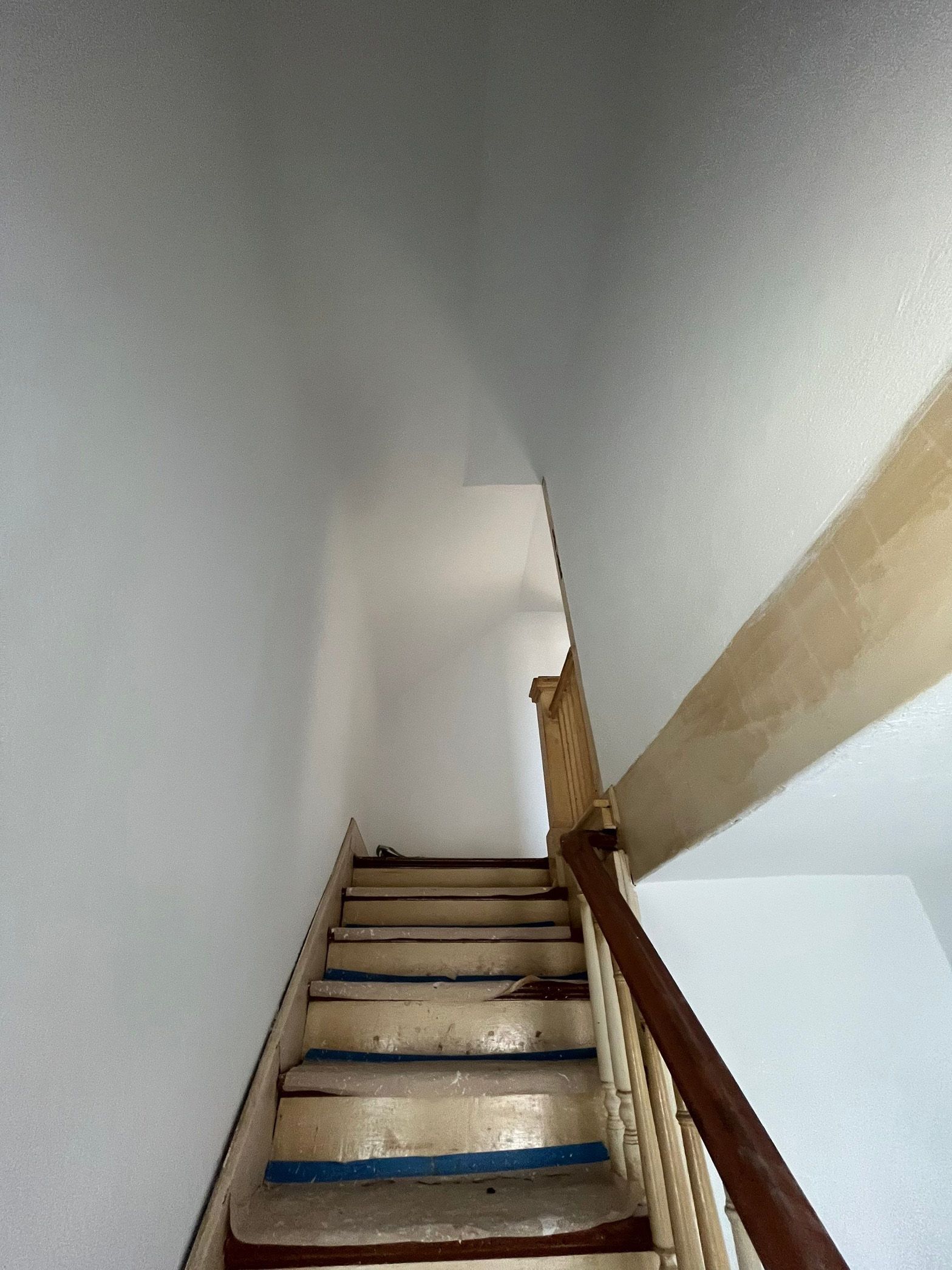 A staircase with a wooden railing and a white wall