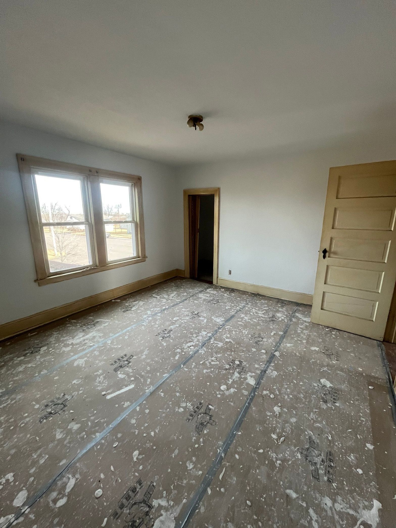 An empty room with a door and two windows.