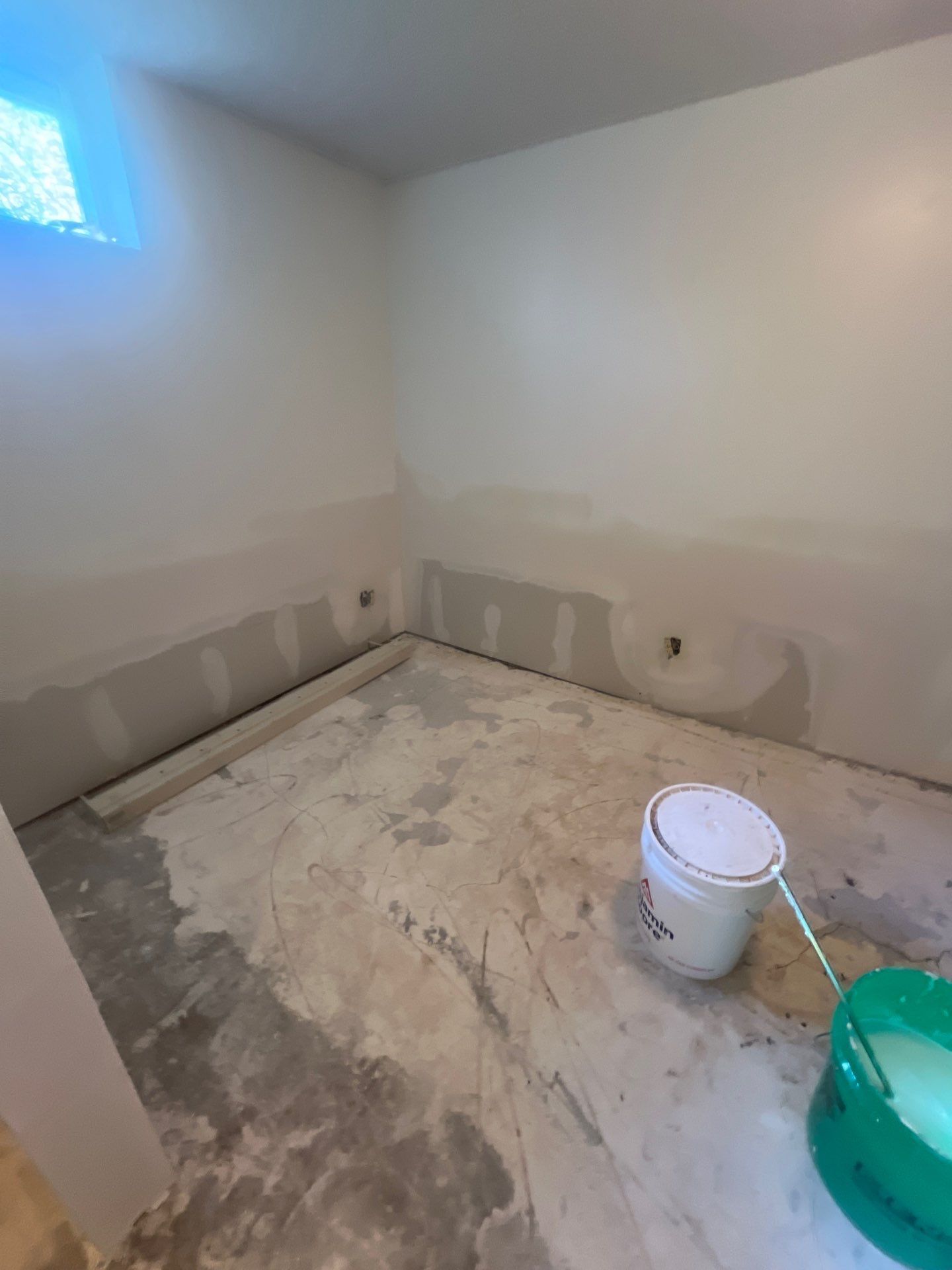 A bucket of paint is sitting on the floor of a room.