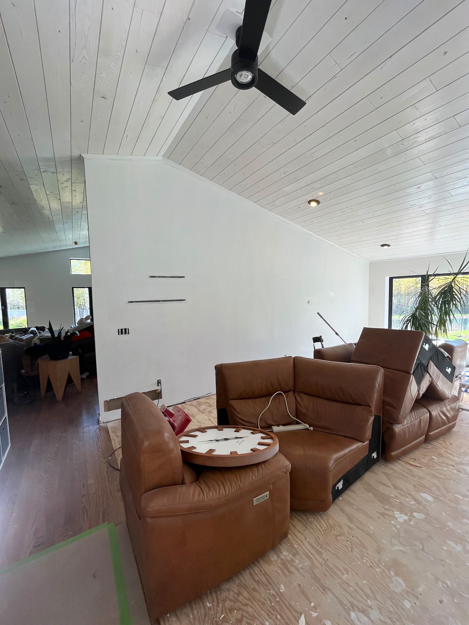 A living room with brown furniture and a ceiling fan