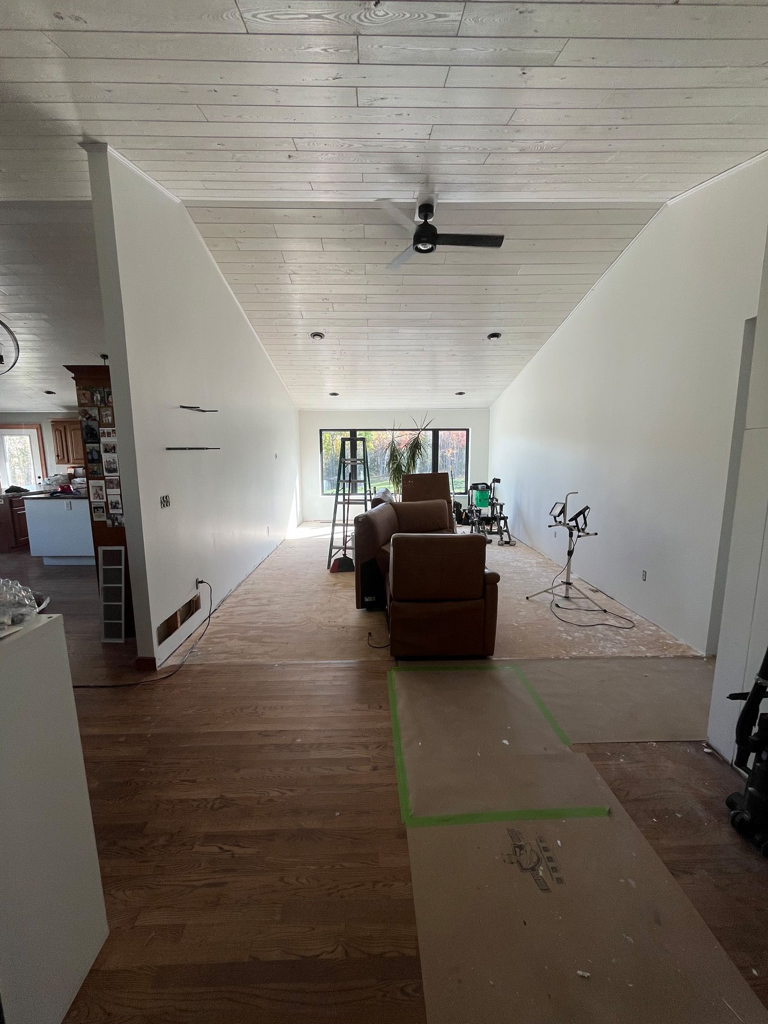 A long hallway leading to a living room with a ceiling fan.