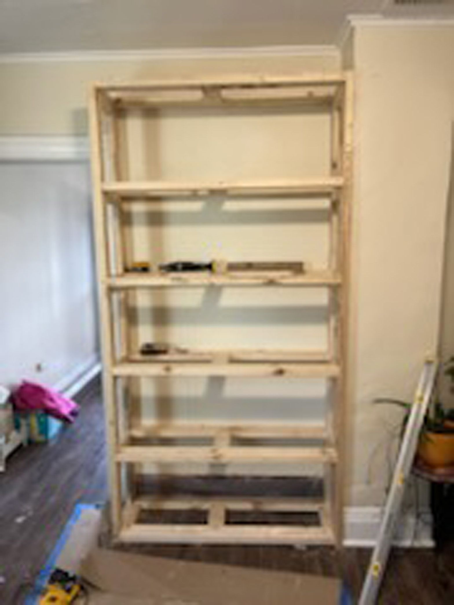 A wooden bookshelf is being built in a living room.