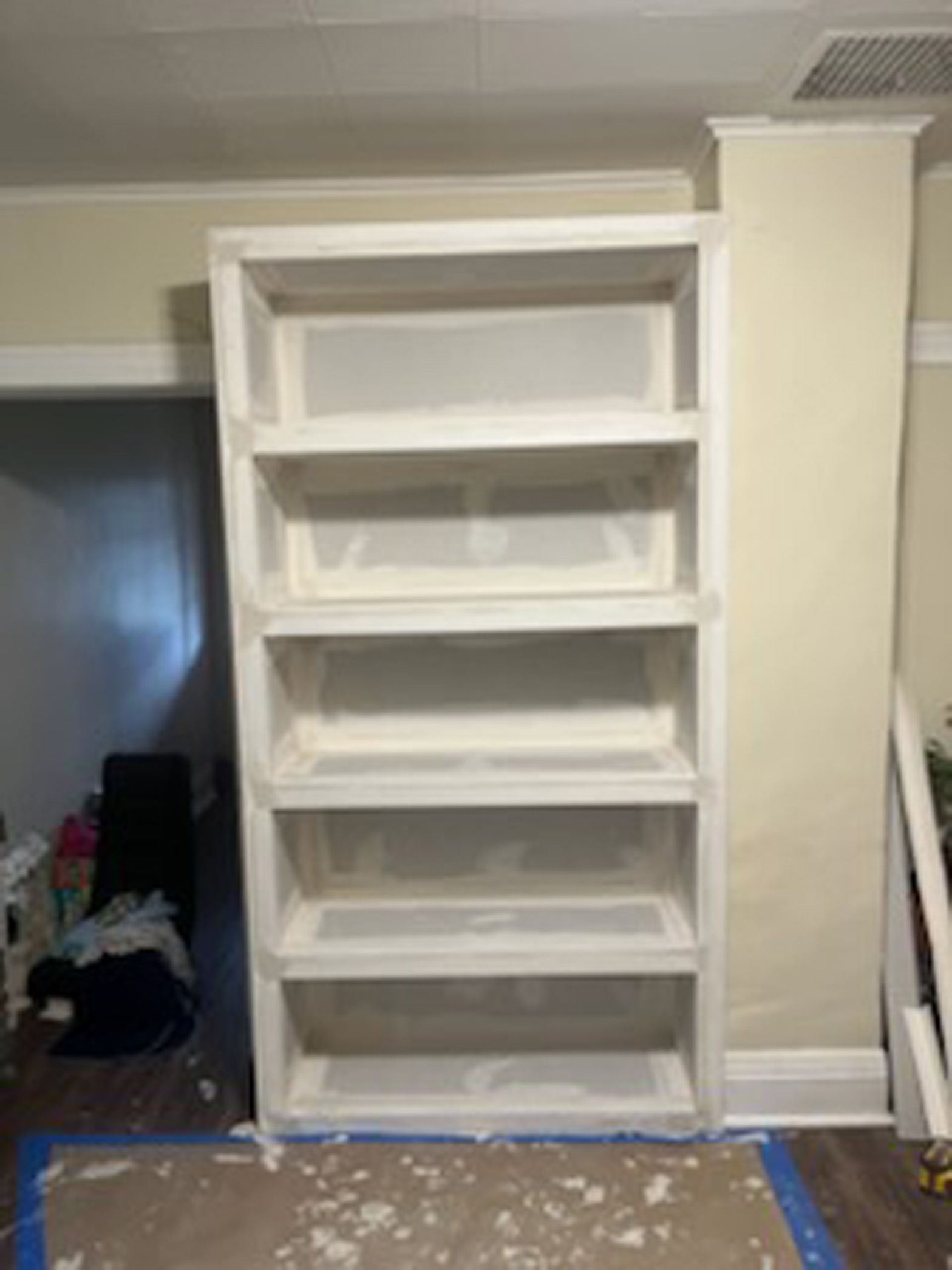A white bookshelf is sitting in a room next to a wall.