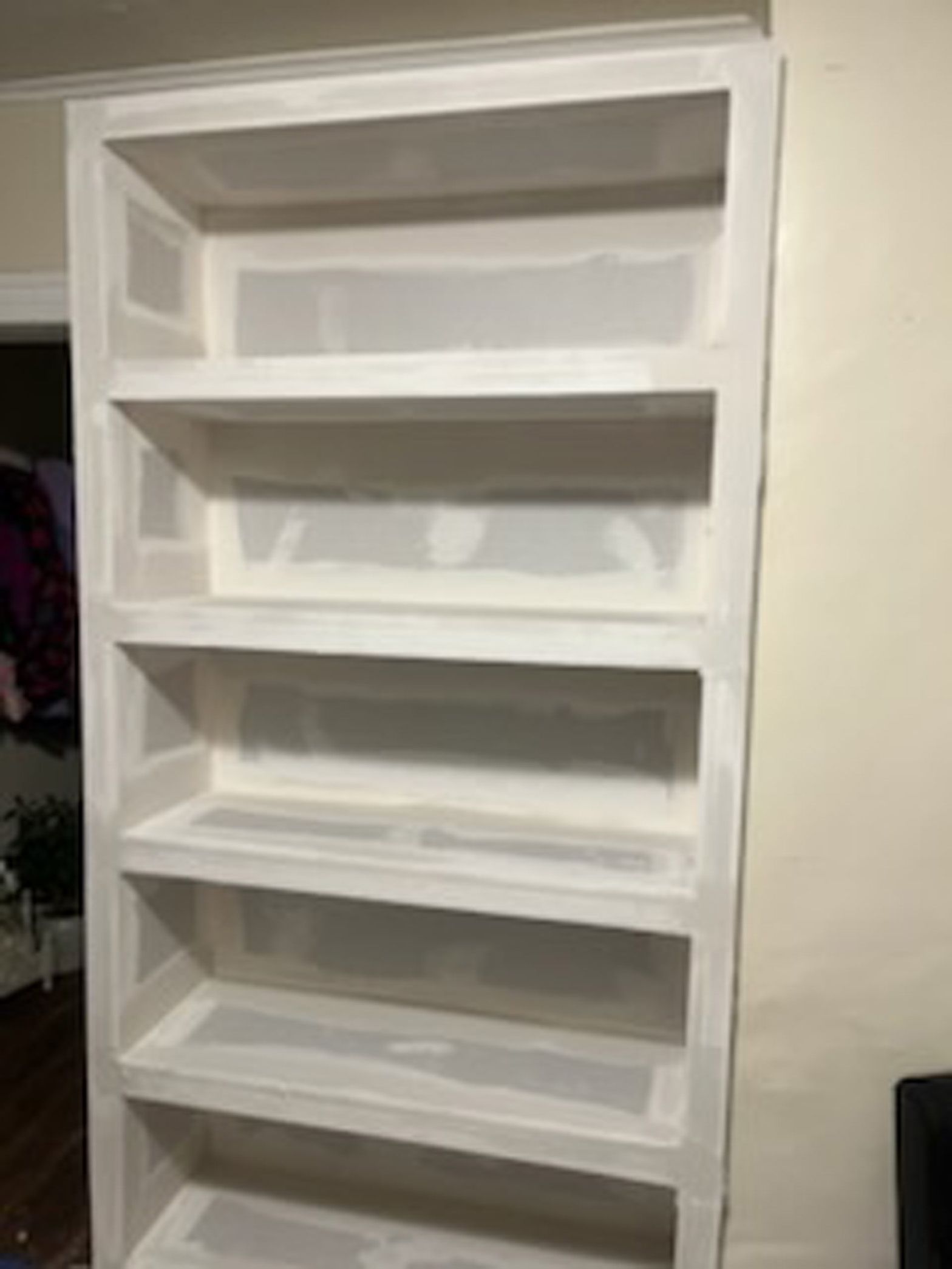 A white bookshelf is sitting in a living room next to a door.