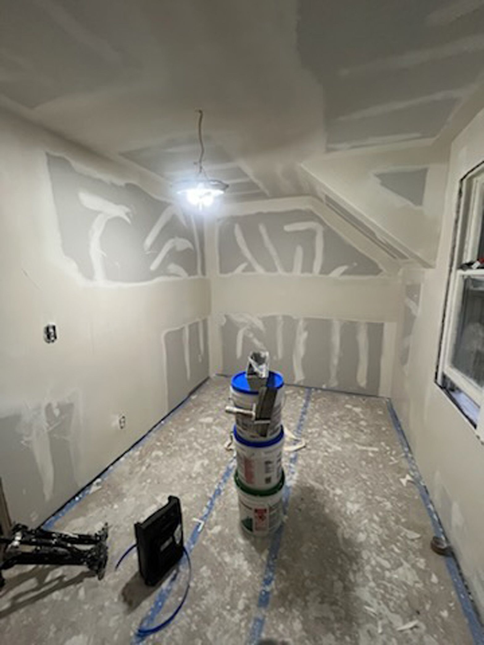 A room that is being painted with buckets of paint on the floor.