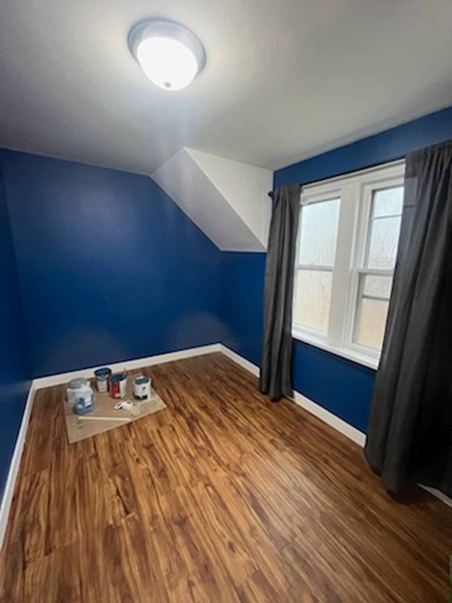 A room with blue walls and wooden floors is being painted.