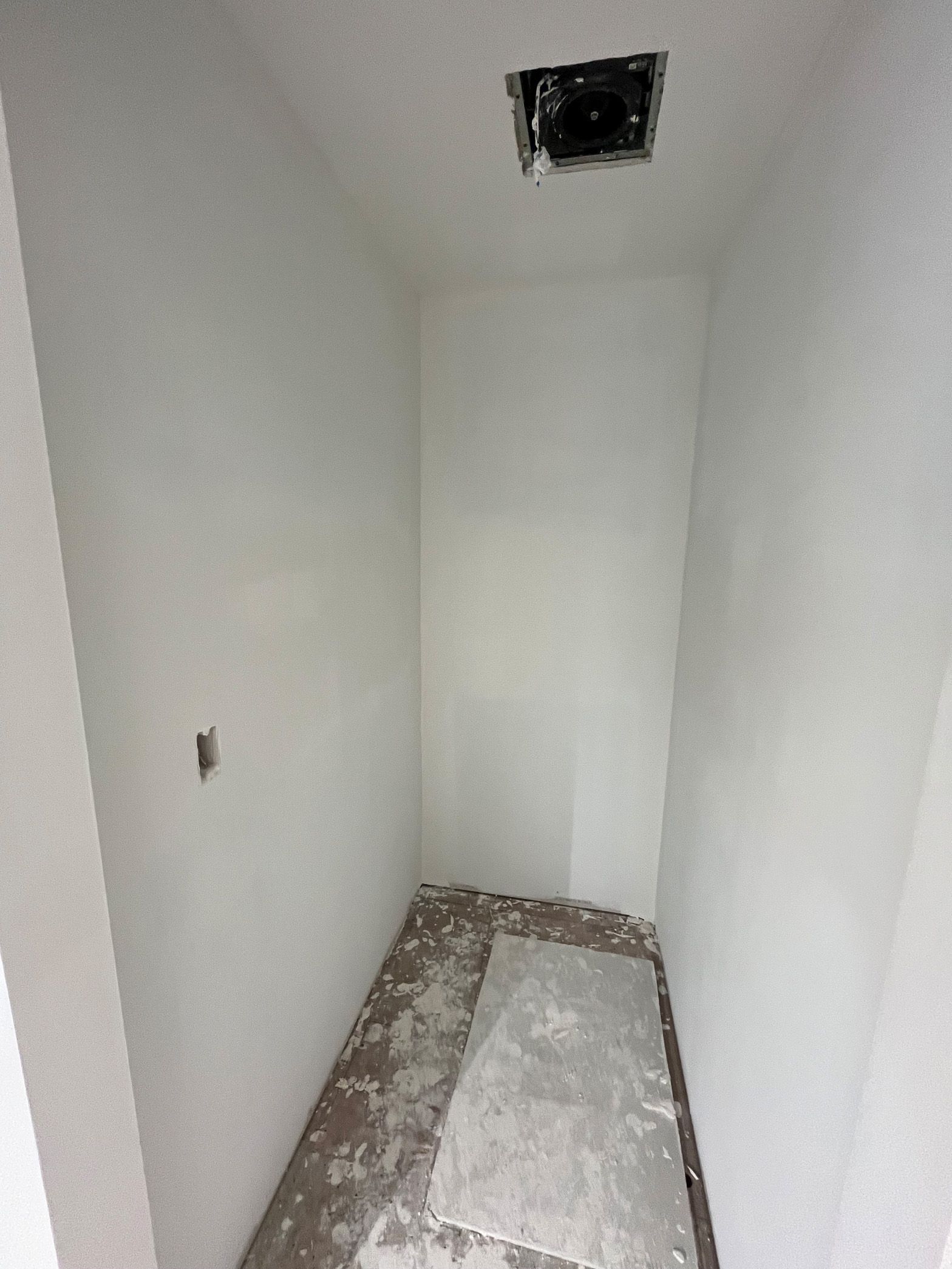 An empty room with white walls and a ceiling fan.