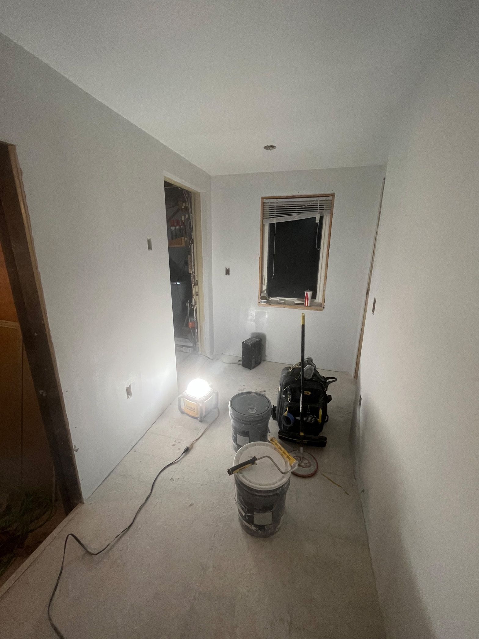 A room with buckets of paint and a vacuum cleaner on the floor.