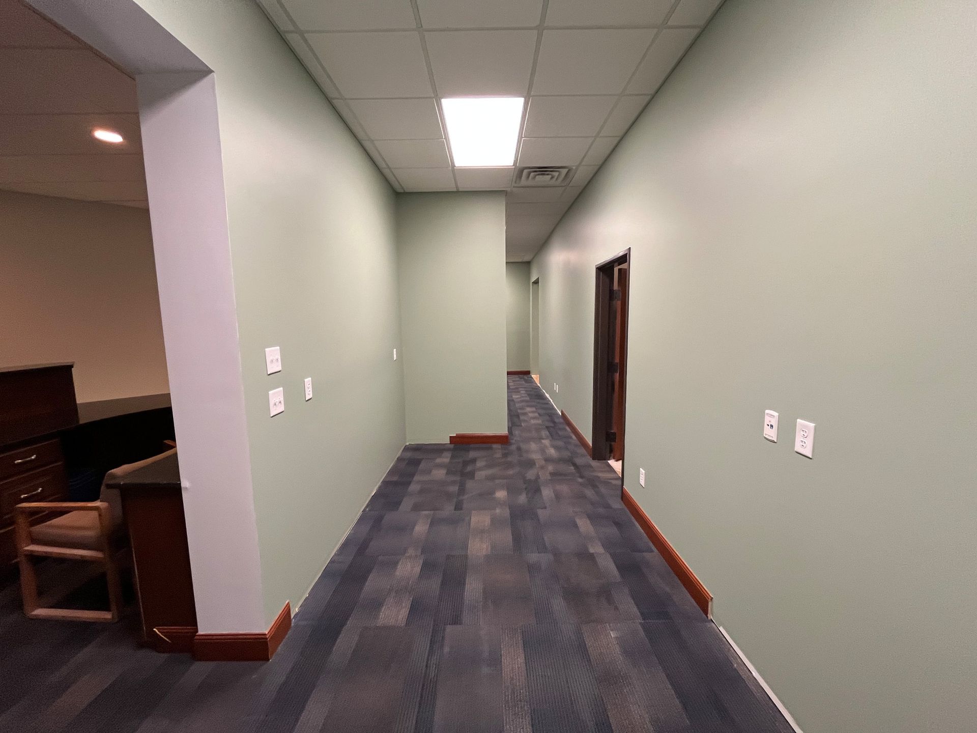 A long hallway with a carpeted floor and green walls