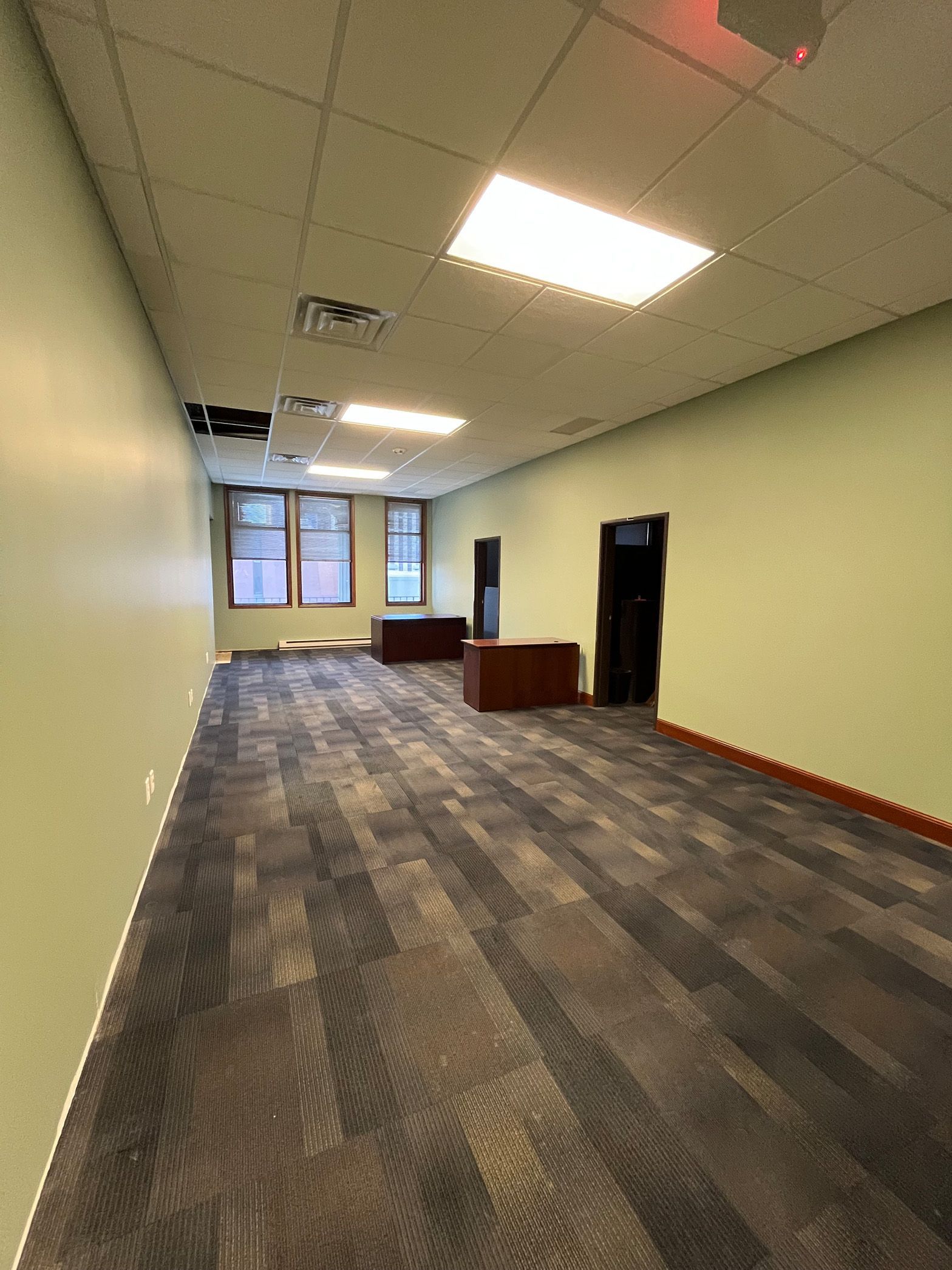 A large empty room with a carpeted floor and a ceiling light.