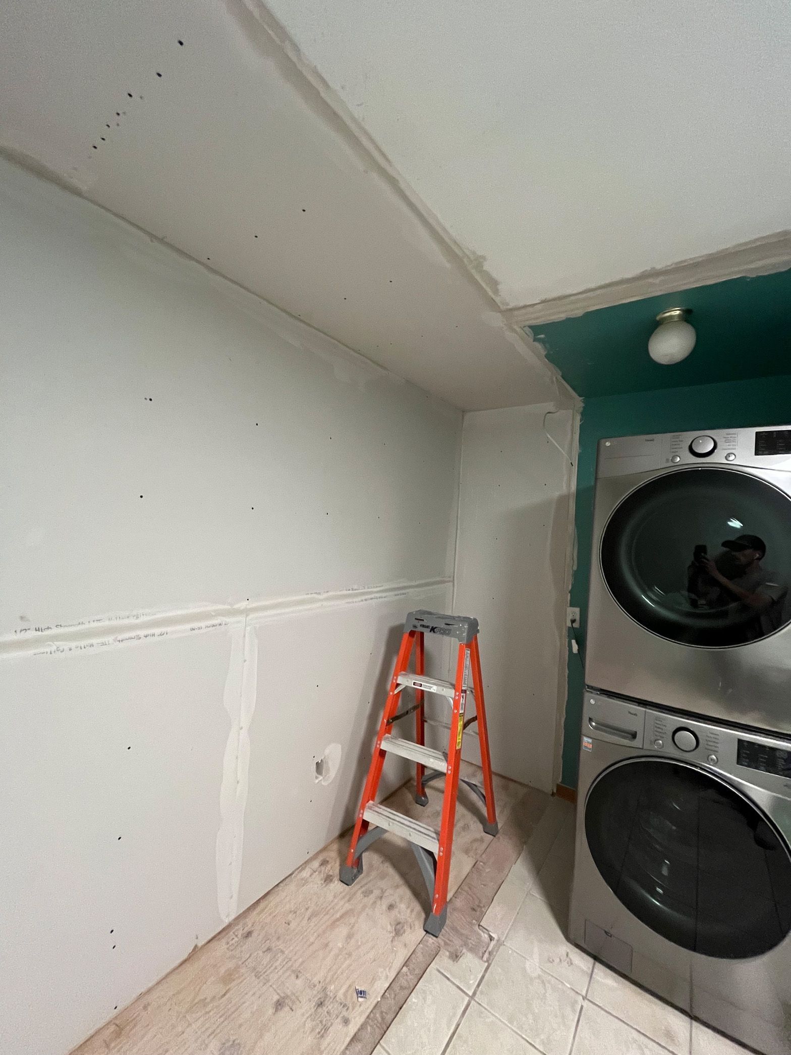 A laundry room with a ladder and a washer and dryer.