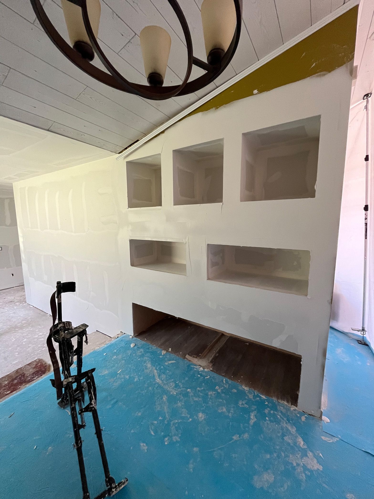 A room with a chandelier hanging from the ceiling and a bicycle on the floor.