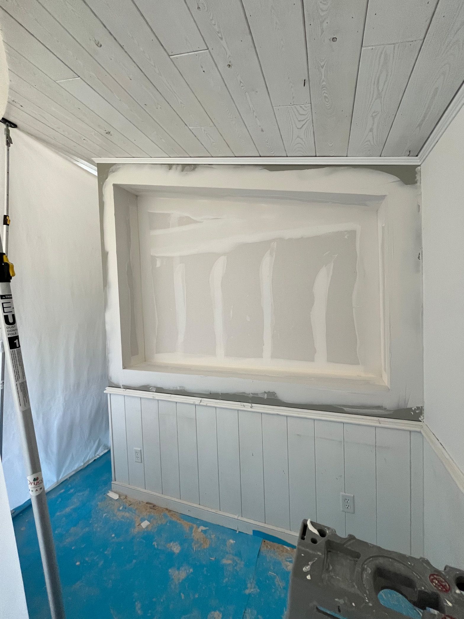 A room with a ladder and a box on the wall.