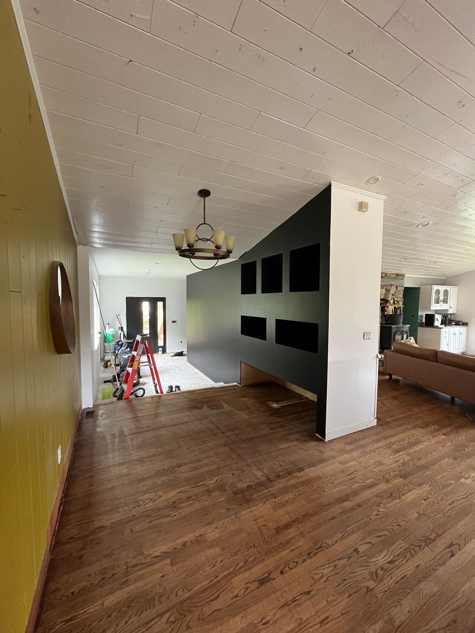 A large empty room with hardwood floors and a chandelier hanging from the ceiling