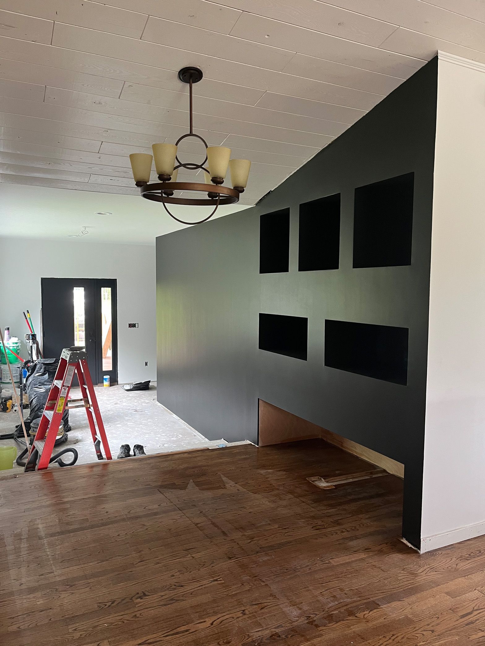 A living room with a black wall and a chandelier hanging from the ceiling.