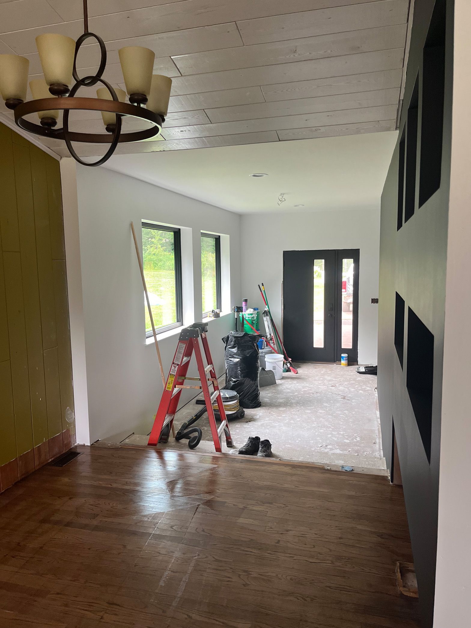 A room with a ladder and a chandelier hanging from the ceiling.