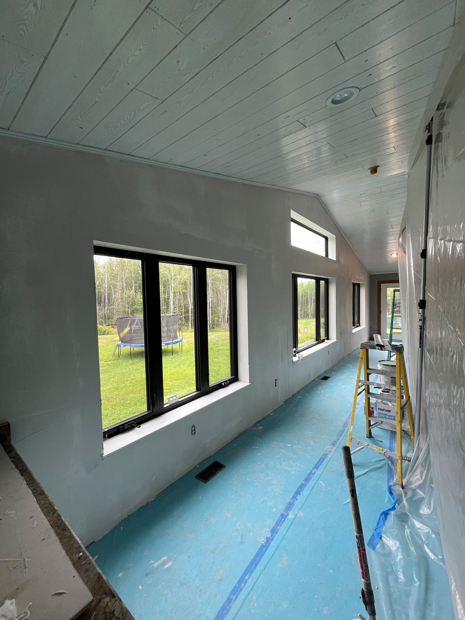 A long hallway with a lot of windows and a ladder.