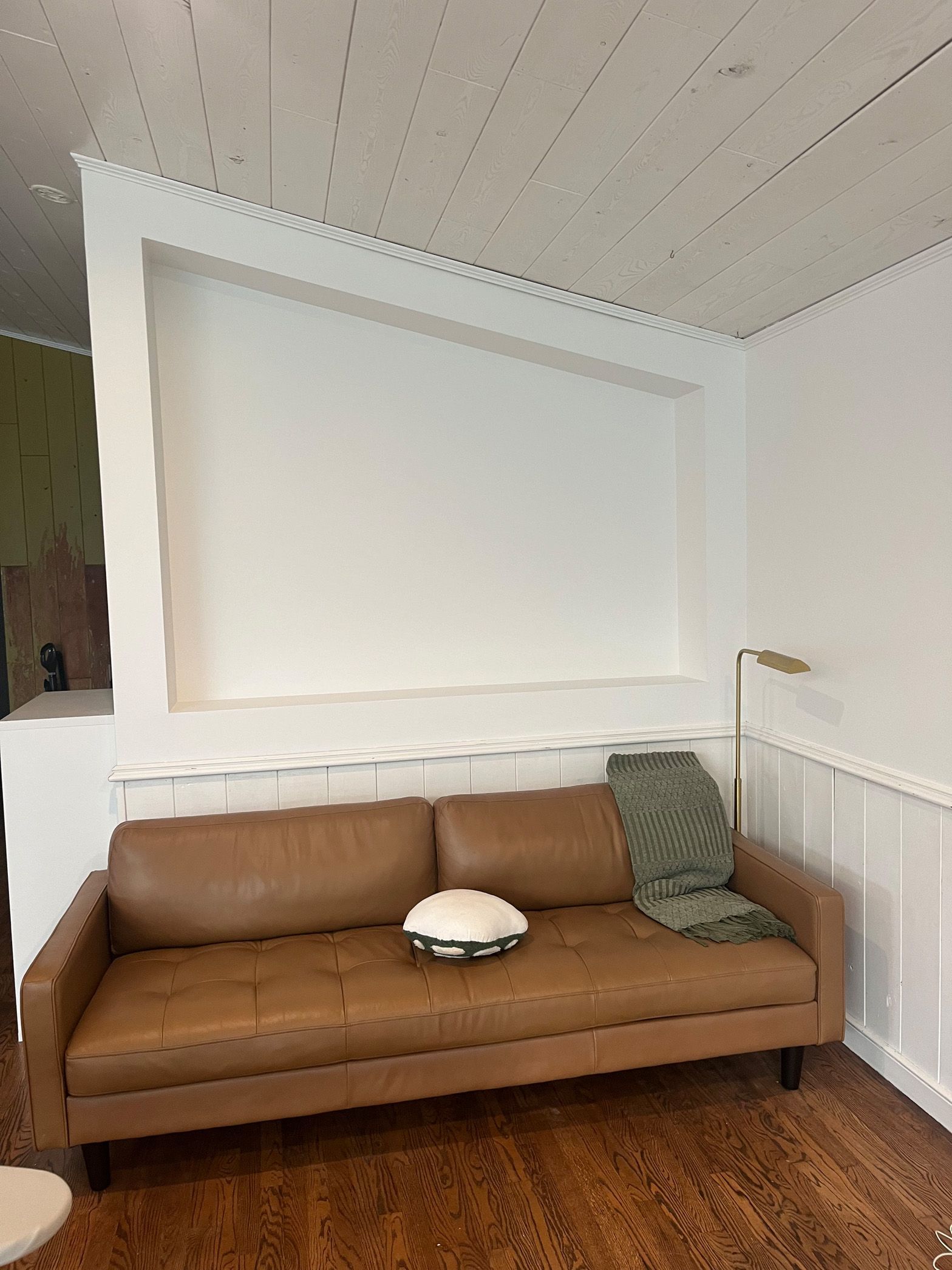 A brown leather couch is sitting in a living room next to a white wall.