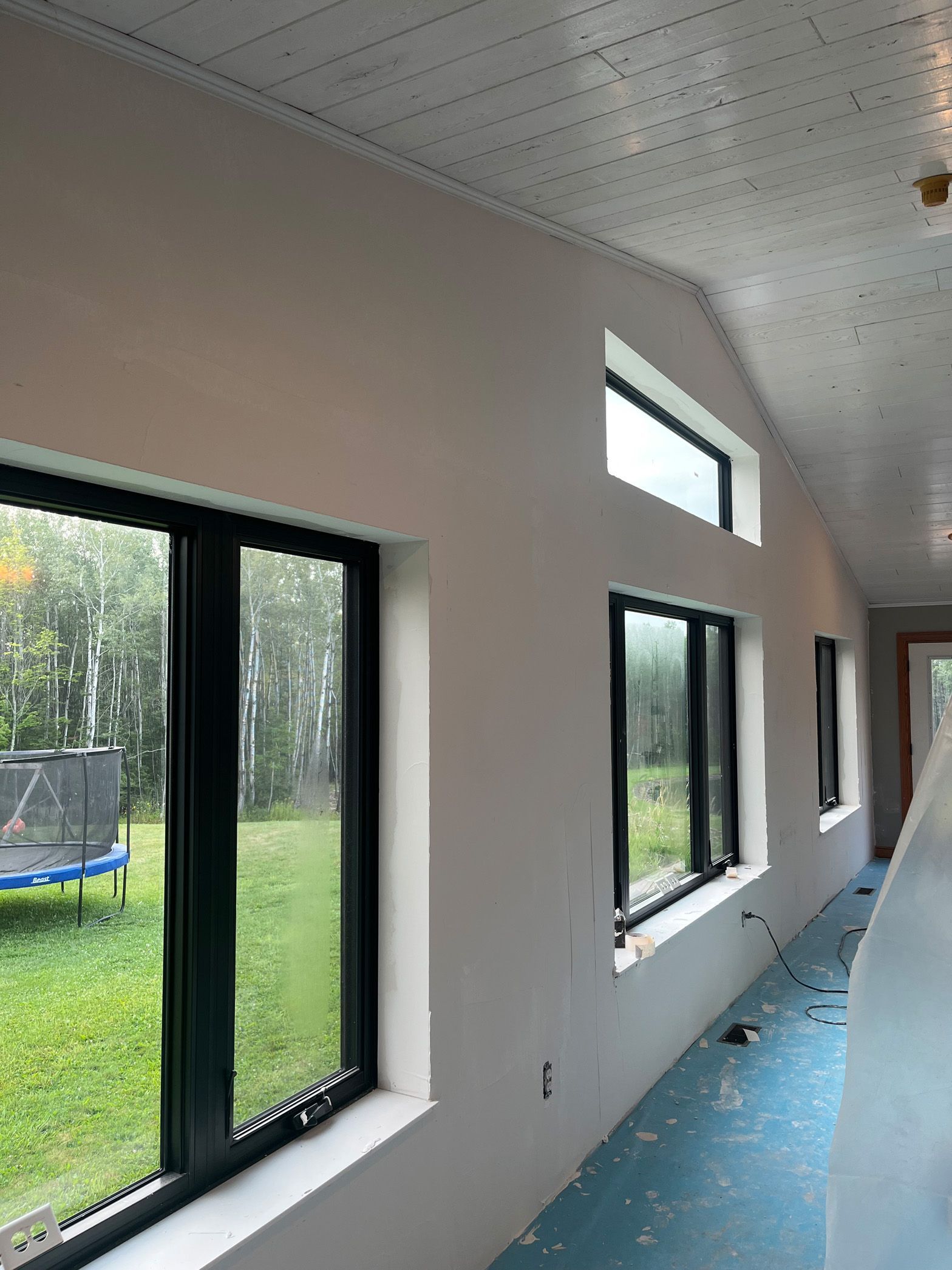 A room with a lot of windows and a trampoline in the background