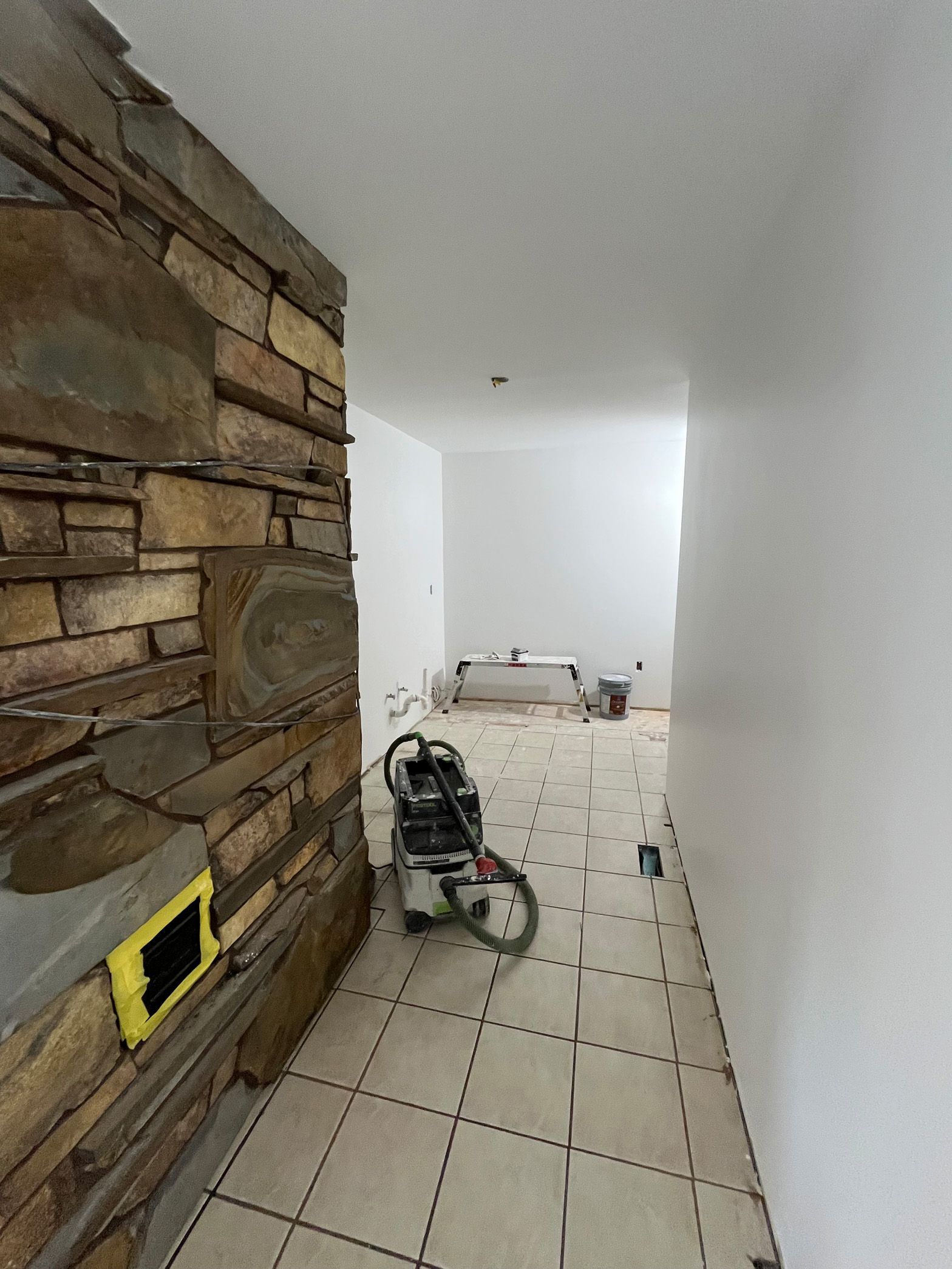 A stroller is sitting in a hallway next to a stone wall.