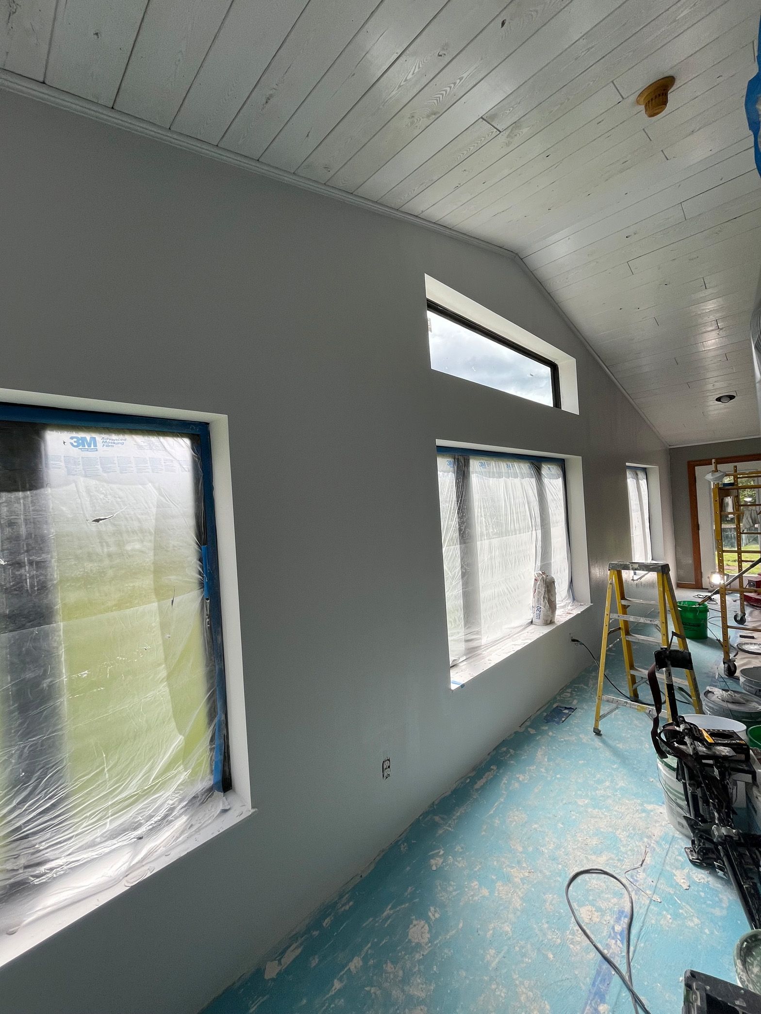 A room with a lot of windows and a ladder in it.