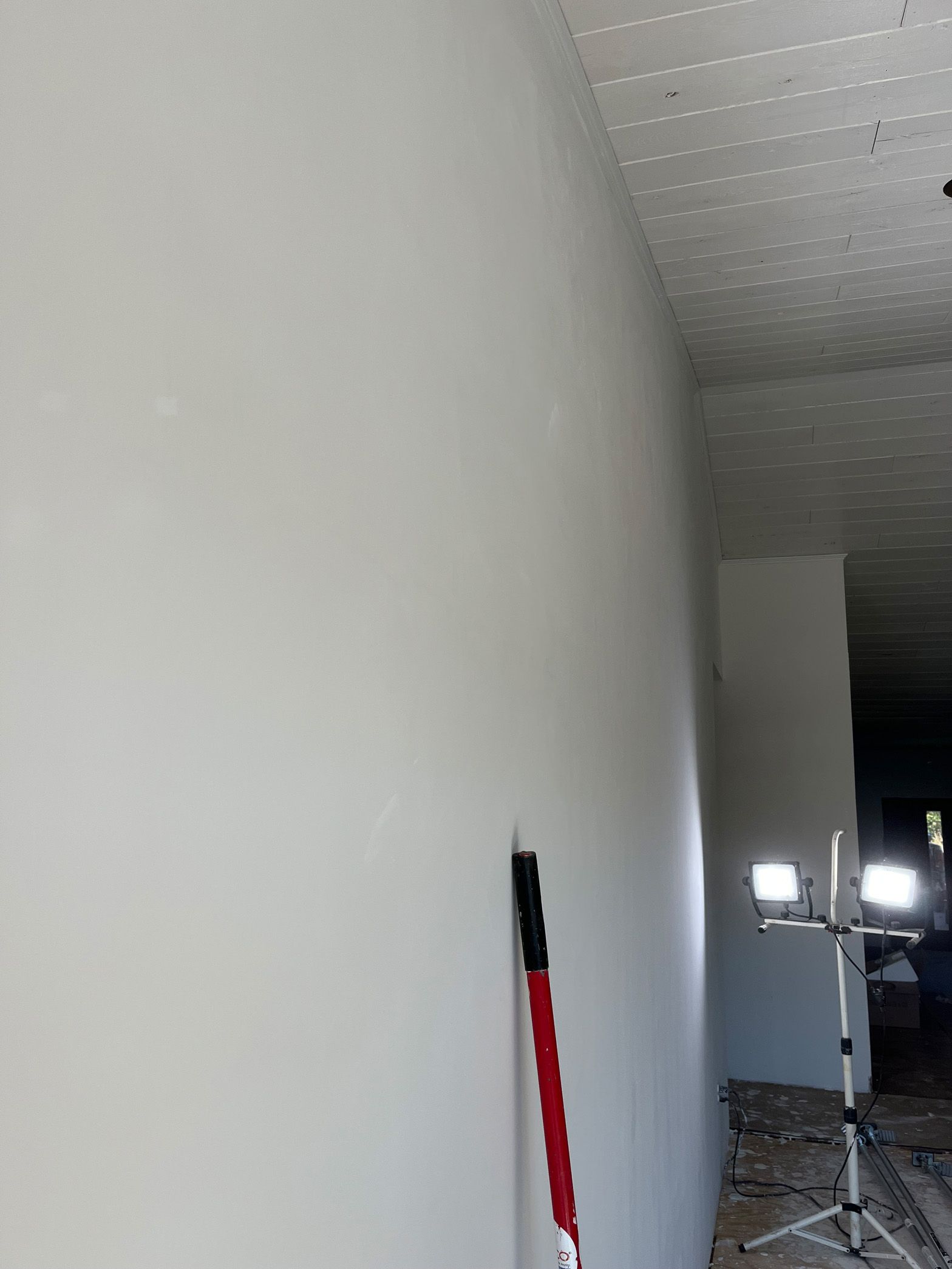 A white wall with a red and black brush on it.