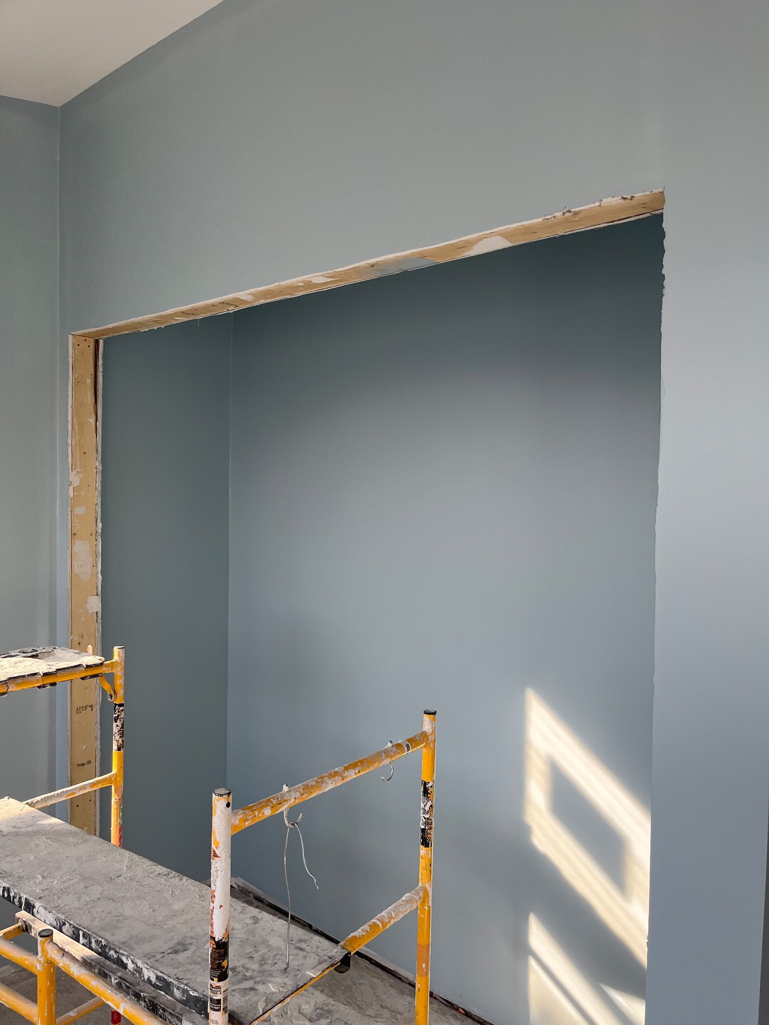 A room with a hole in the wall and a scaffolding in front of it.