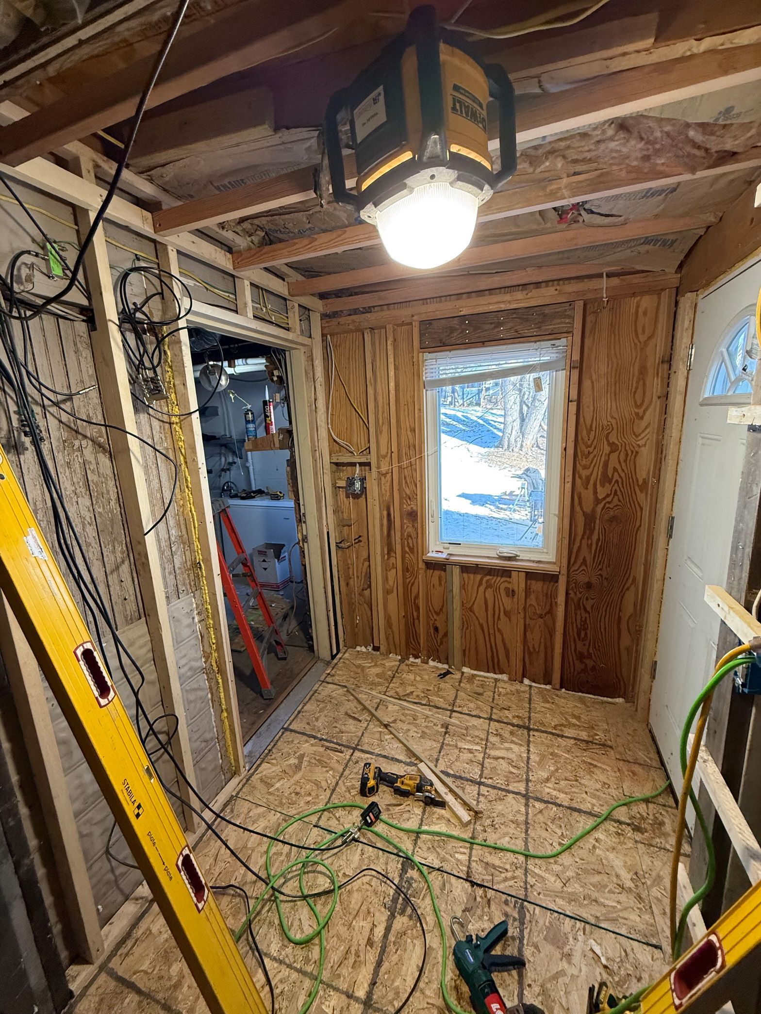 A room with a lot of wires hanging from the ceiling and a ladder.