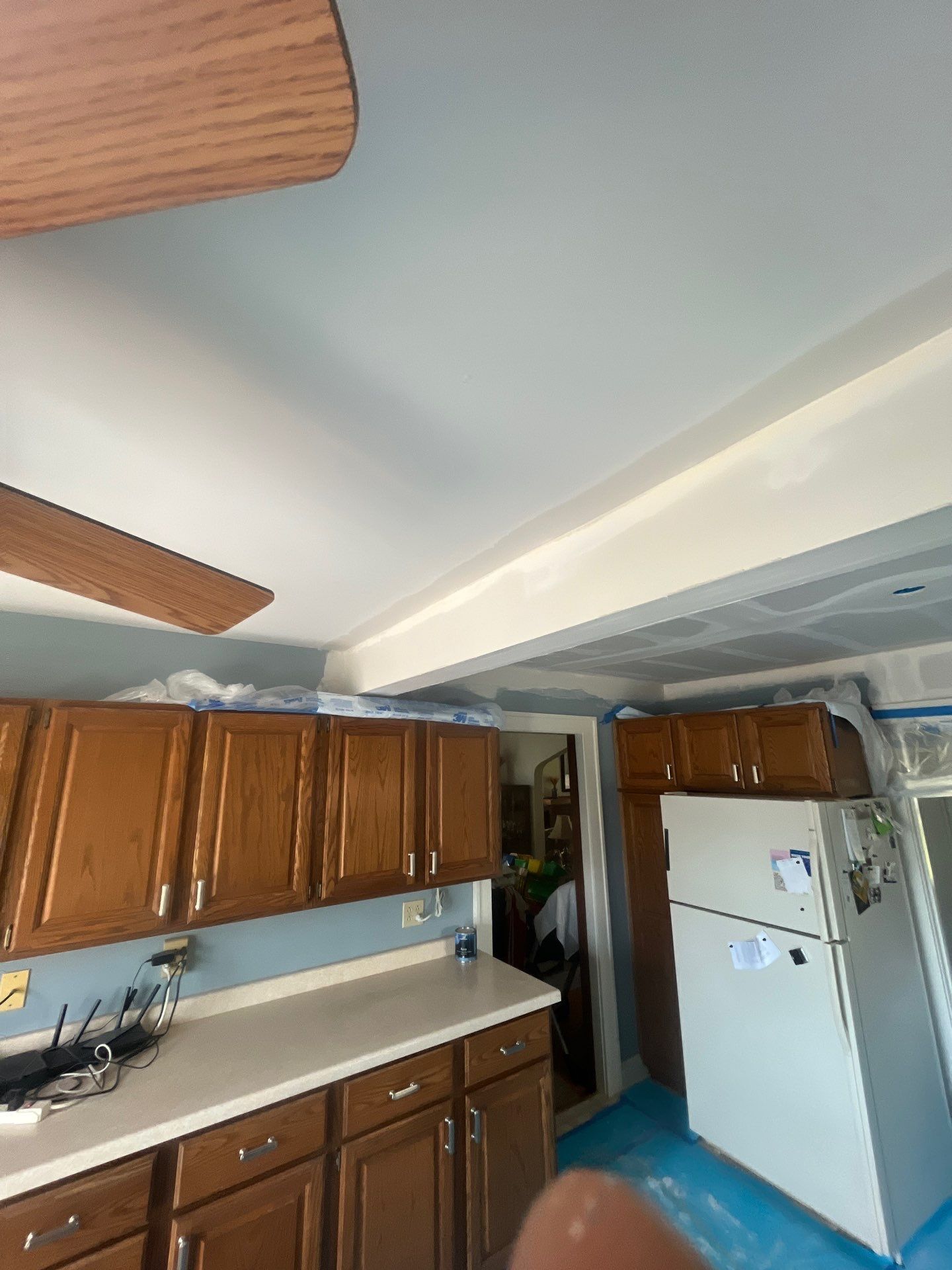 A kitchen with wooden cabinets , a refrigerator , and a ceiling fan.