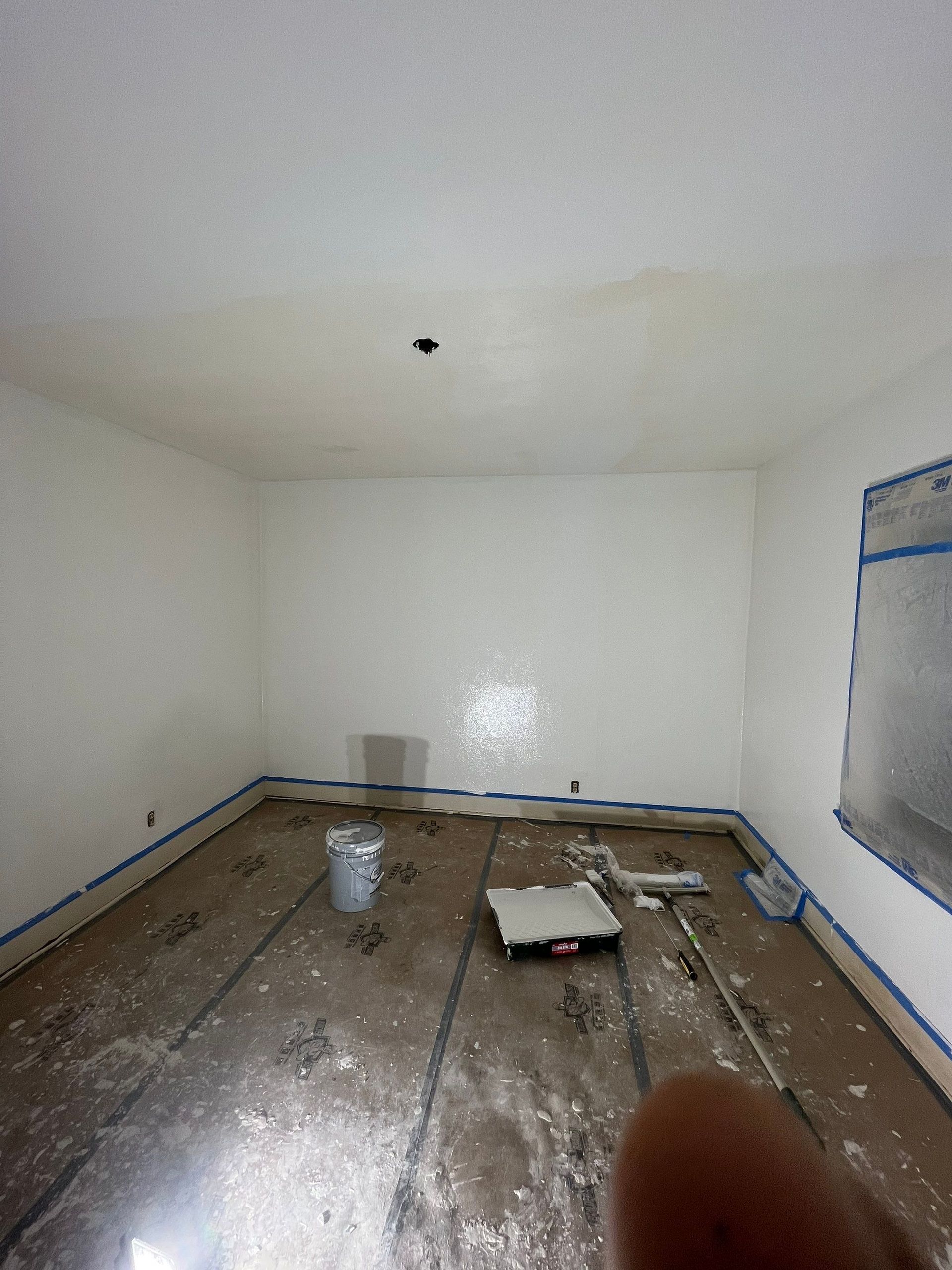 A room with white walls and a bucket of paint on the floor