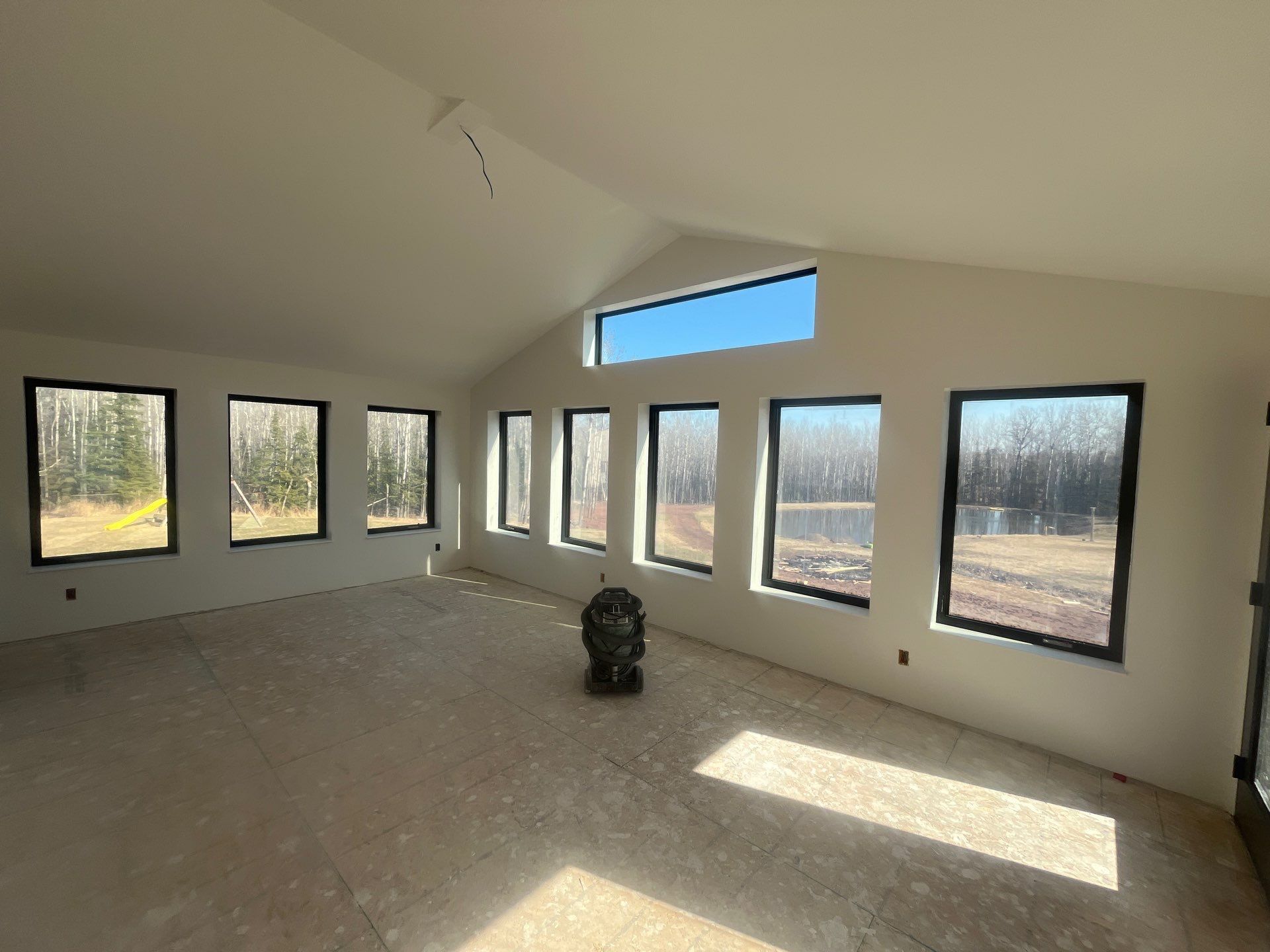 A room with drywall on the walls and a bucket of paint on the floor.