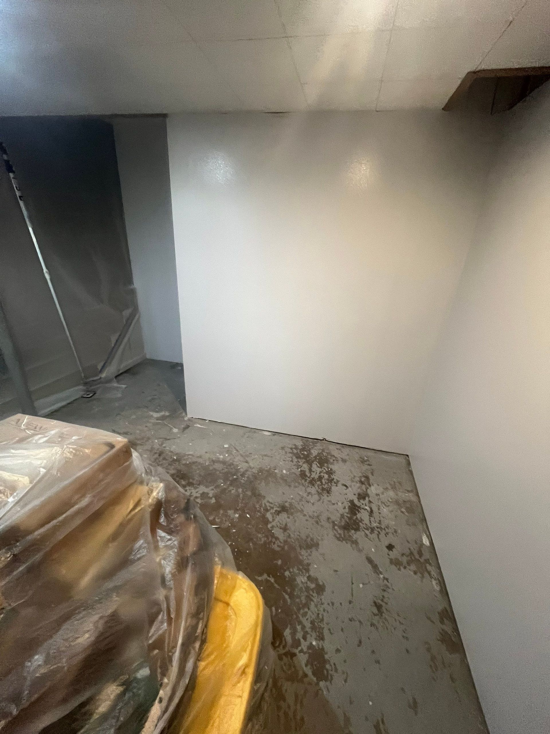 A room with white walls and a yellow trash can in it.