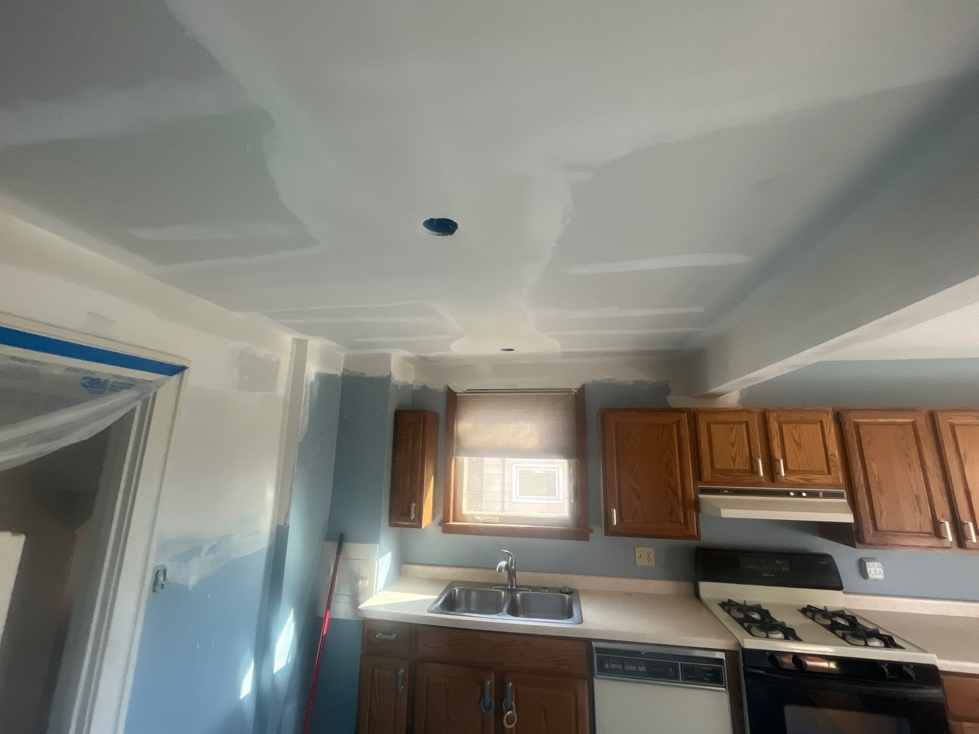 A kitchen with wooden cabinets , a stove , a sink , and a window.