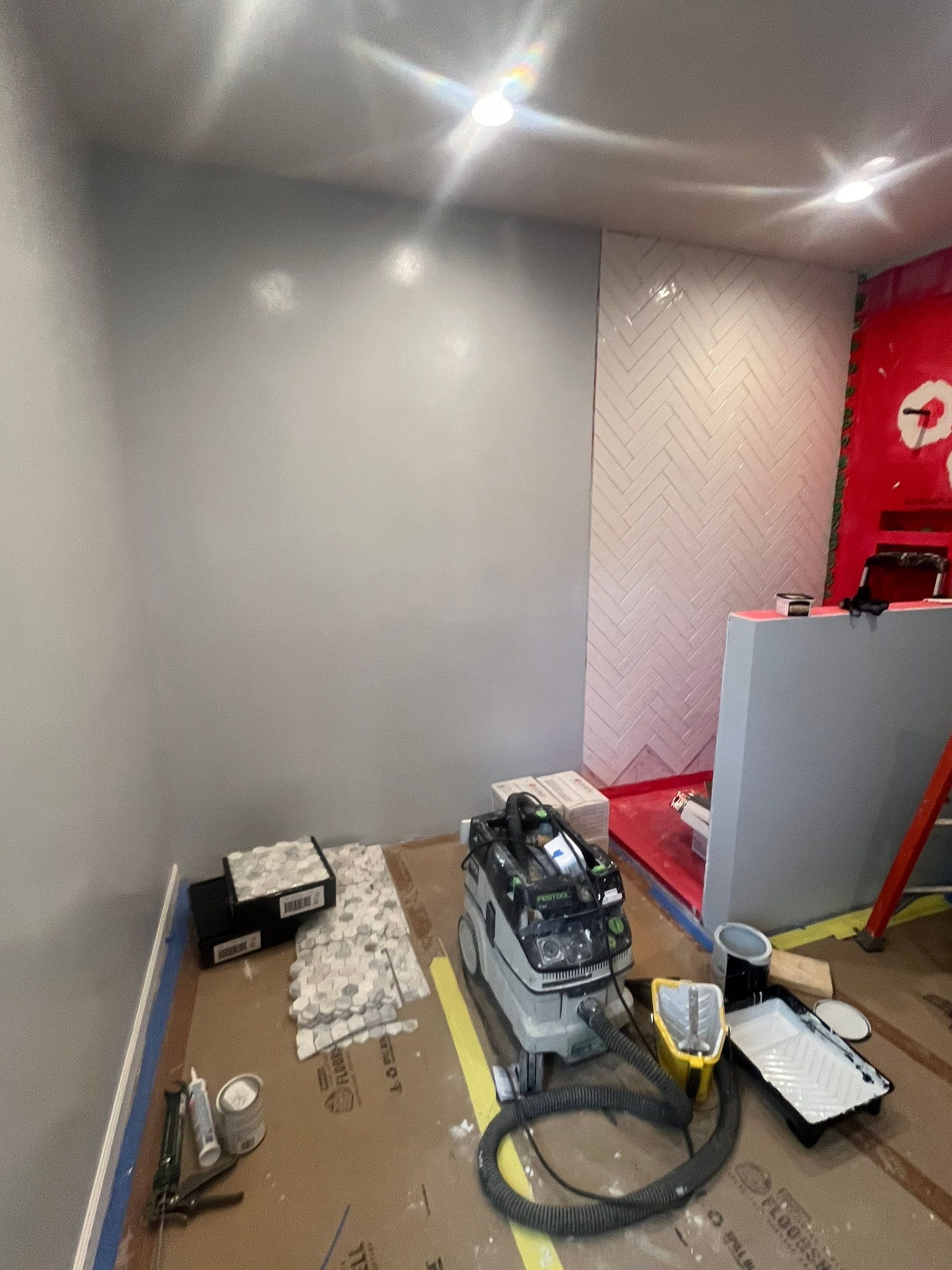 A room that is being painted with a vacuum cleaner on the floor