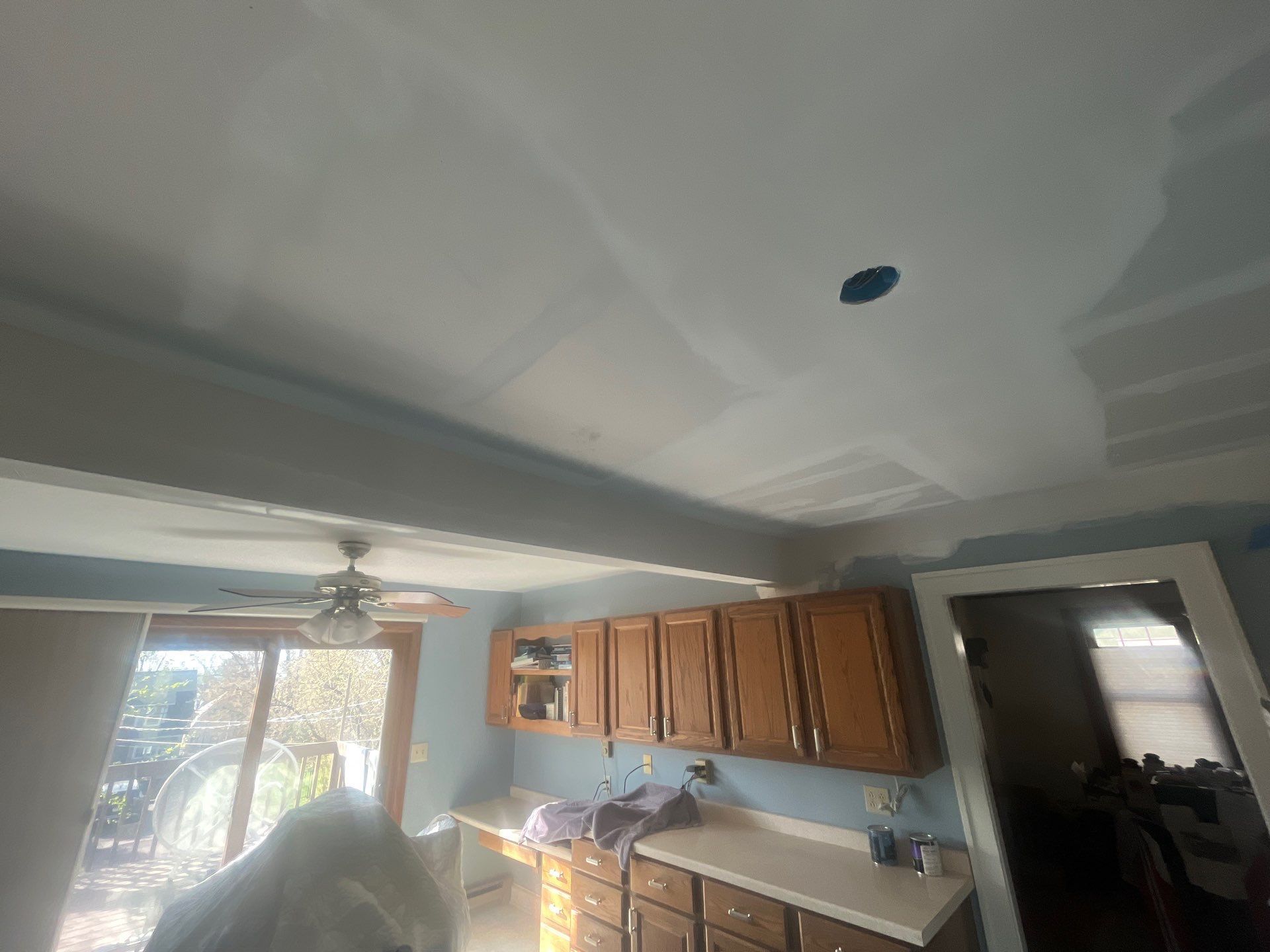 A kitchen with wooden cabinets and a ceiling fan.