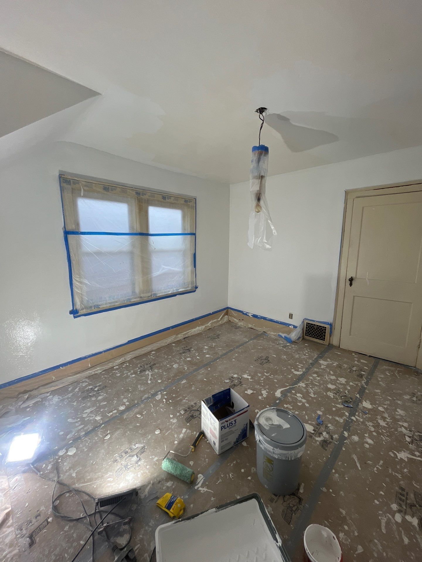 A room with white walls and a window is being painted.