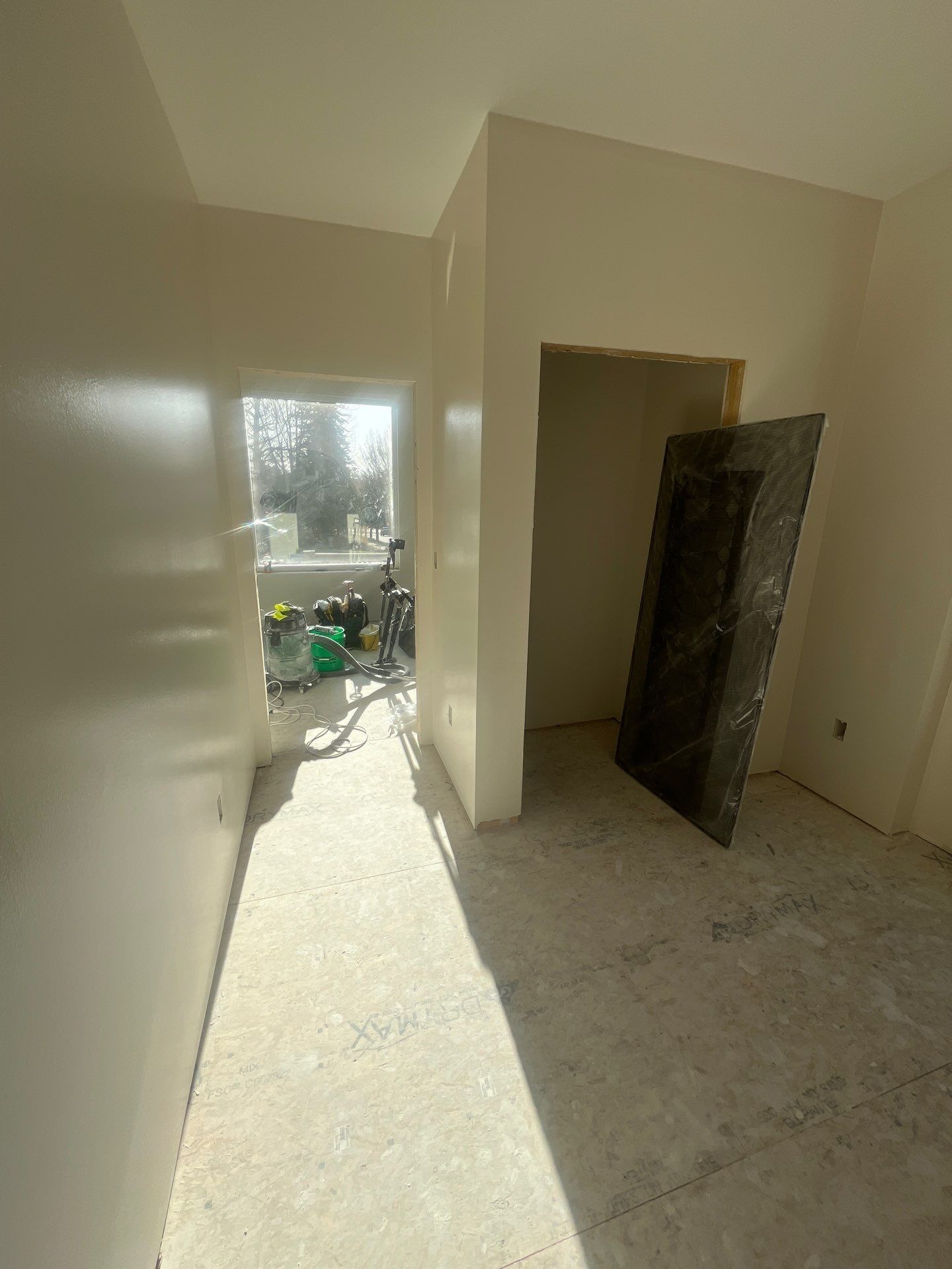 An empty room with a door and a window in a house under construction.