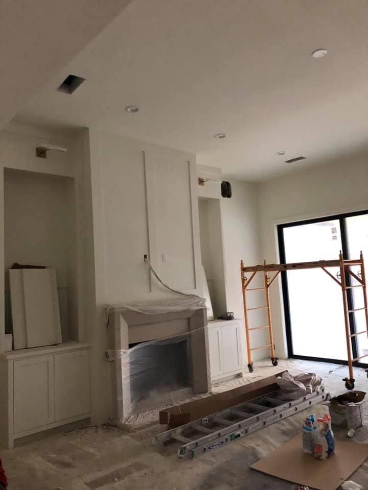 A living room with a fireplace and a ladder in it.