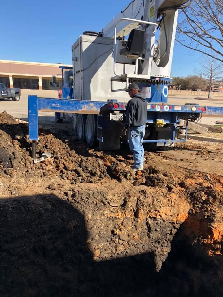 A man is standing in the dirt next to a large truck.